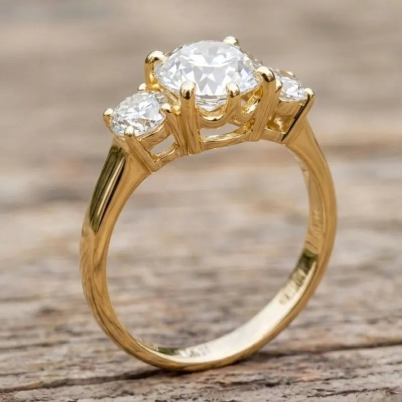 Gold ring with three diamonds on a wooden surface